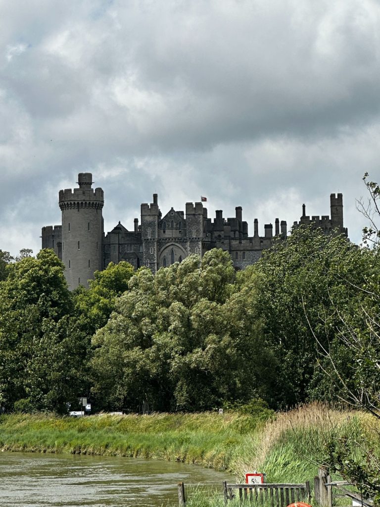 Arundel Castle behind some trees with the river in front of it. the sky is grey and cloudy